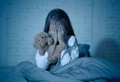 Scared child in bed - prevent child maltreatment